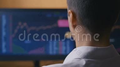 男商人正在电脑显示器上研究销售图表。 经纪人正在看股票销售统计